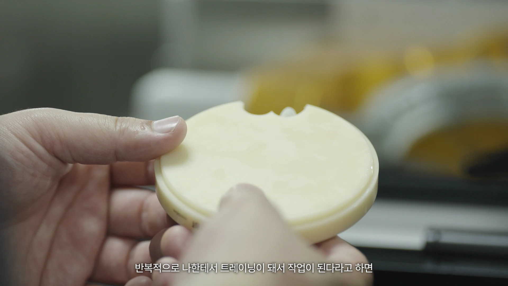 작은 원형 받침을 손에 들고 살펴보는 기공실장의 손